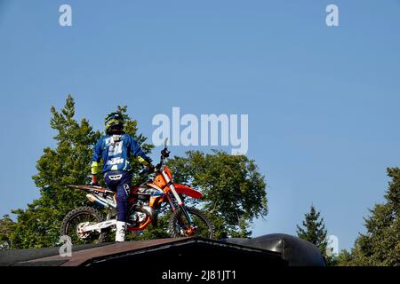 Praga, Repubblica Ceca - Settembre 4 2021: Pilota di Motocross in una tuta blu con un casco seduto sulla sua moto in cima alla rampa di salto. Foto Stock