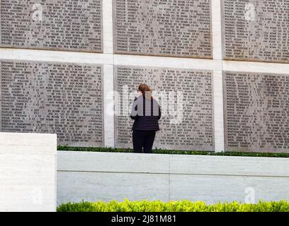 Giovane donna cerca i 1409 nomi dei saldatori mancanti sulle tavolette del muro mancante al cimitero e memoriale americano di Firenze, Toscana, IT. Foto Stock