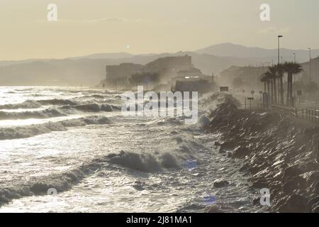 Onde mare che si infrangono contro le rocce al tramonto Foto Stock