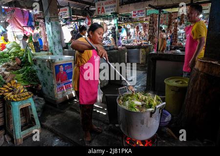 San Jose, Filippine - Maggio 2022: Una donna che prepara il cibo al mercato di San Jose il 3 maggio 2022 a San Jose, Occidental Mindoro, Filippine. Foto Stock