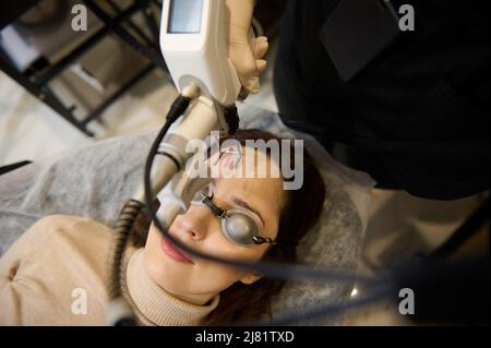 Estetista estetista utilizzando la maniglia laser sul viso della donna di mezza età, mentre facendo il laser pelle resurfacing in medicina estetica Foto Stock