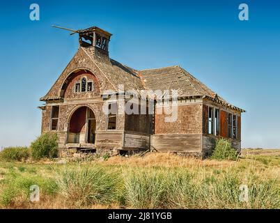 La vecchia scuola si trova vuota nei campi della città fantasma di Govan, Washington. La città è il luogo di diversi omicidi di ascia irrisolti. Foto Stock