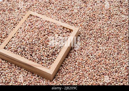 Un fondo con sorgo accatastato e una ciotola di legno contenente sorgo. Foto Stock