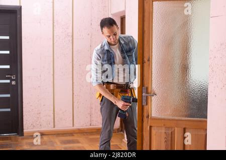 Giovane uomo in uniforme cambio serratura porta Foto Stock