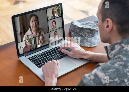 Un uomo soldato felice sorridendo mentre si fa una chiamata in conferenza su un computer portatile al chiuso Foto Stock