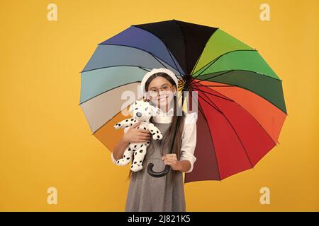 felice adolescente sotto ombrello colorato nella stagione autunnale tenere giocattolo, felice infanzia. Foto Stock