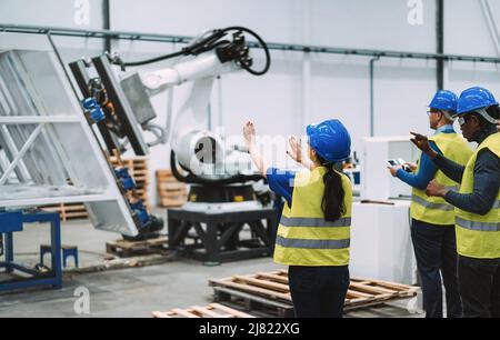 Ingegneri multietnici che utilizzano occhiali futuristici per realtà aumentata all'interno di una fabbrica robotica - concetto industriale e tecnologico - Focus on Senior Woman ha Foto Stock