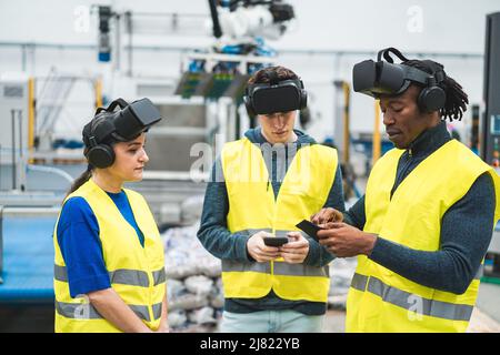 Ingegneri multietnici che utilizzano cuffie per realtà virtuale all'interno di una fabbrica robotica - concetto industriale e tecnologico - Focus morbido sulla mano superiore dell'uomo africano Foto Stock