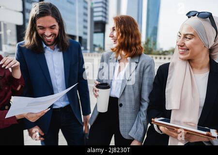 Uomini d'affari multietnici che lavorano all'aperto dall'edificio di uffici - Focus principale sugli occhiali da sole musulmani Foto Stock
