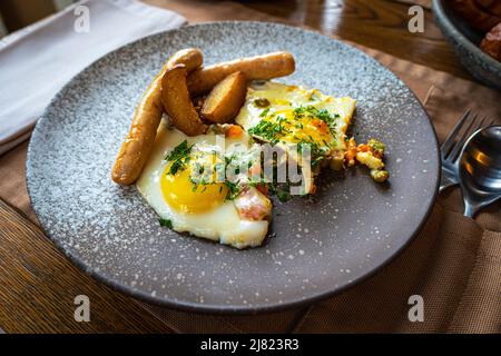 prima colazione con uova fritte accompagnate, salsiccia piccola e uova strapazzate. Colazione inglese tradizionale europea. Foto Stock