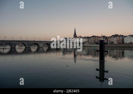 Splendida vista serale dello skyline e delle vecchie case cittadine lungo il lungofiume che si riflette nel fiume Maas a Maastricht, nei Paesi Bassi Foto Stock