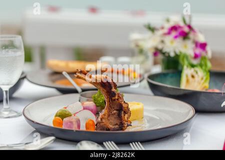 Rack di agnello arrosto con purè di patate e cipolle al tavolo nel ristorante di lusso Foto Stock