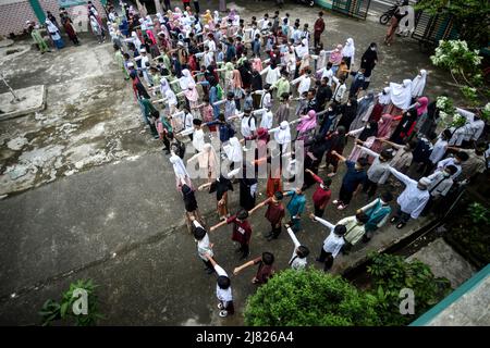 Tangerang sud, Indonesia. 12th maggio 2022. Gli studenti elementari si accodano seguendo le distanze fisiche come sforzi preventivi attraverso l'implementazione di un comportamento di vita pulito e sano (PHBS) durante il primo giorno di scuola dopo la vacanza di Eid al-Fitr al villaggio di Serua a South Tangerang, provincia di Banten, Indonesia, 12 maggio 2022. Credit: Agung Kuncahya B./Xinhua/Alamy Live News Foto Stock