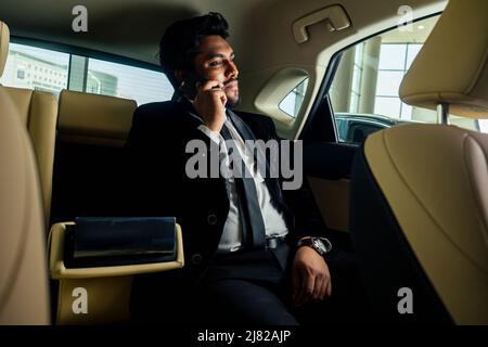 Ricco uomo d'affari indiano in auto di guida di usura formale Foto Stock