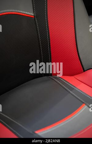 Moderna vettura sportiva con interni in pelle nera e rossa. Parte dei dettagli dei sedili in pelle con cuciture bianche. Foto Stock