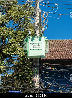 Gramado, Brasile - Circa Aprile 2022: Cavi elettrici disordinati su un palo per utenze, con trasformatore ecologico Itaipu Foto Stock