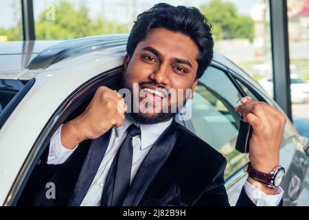 happy business uomo indiano in vestito nero vestito vestire nuovo biodiesel eco automobile in lux showroom Foto Stock