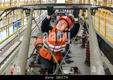 Datong, la provincia cinese di Shanxi. 12th maggio 2022. Un lavoratore controlla il sistema di catenaria di un treno merci in una base di manutenzione a Datong, nella provincia cinese settentrionale di Shanxi, il 12 maggio 2022. Per assicurare un trasporto sicuro e regolare sulla ferrovia di Datong-Qinhuangdao, i lavoratori della ferrovia cinese Taiyuan Group Co., Ltd. Effettuano la manutenzione regolare sui treni di trasporto pesante dopo la consegna del carico. Credit: CaO Yang/Xinhua/Alamy Live News Foto Stock