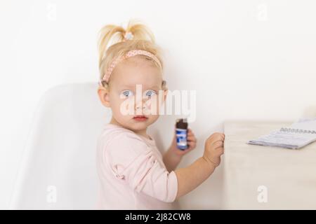 Bambino con impianto cocleare seduto a casa e mangiare. Ascolta il concetto di tecnologia innovativa di aiuto e medicina Foto Stock