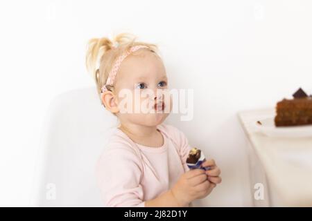 Bambino con impianto cocleare seduto a casa e mangiare. Ascolta il concetto di tecnologia innovativa di aiuto e medicina Foto Stock