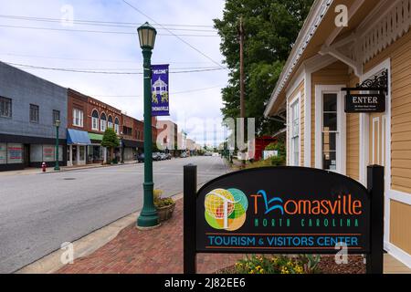 THOMASVILLE, NC, USA-8 MAGGIO 2022: Thomasville Tourism & Visitors Center, segnaletica multipla, caboose rossa, vista lungo Main Street. Foto Stock