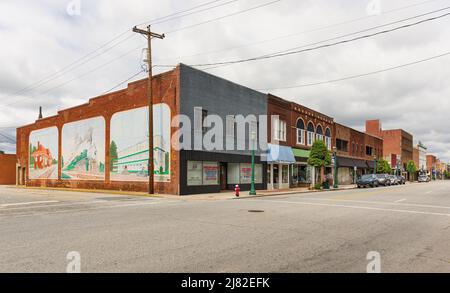 THOMASVILLE, NC, USA-8 MAGGIO 2022: Main Street, vista diagonale degli edifici, murale di scene storiche sulla parete di fondo. Foto Stock