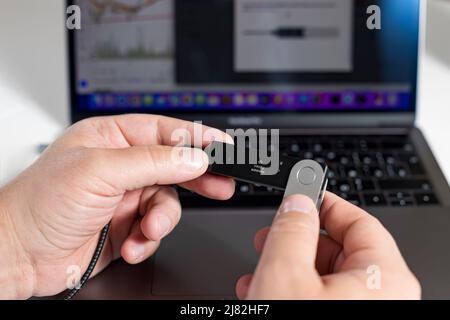 Russia, Krasnodar - 15 aprile 2022: Uomo che conferma la transazione nella catena intelligente Binance utilizzando il portafoglio di criptovaluta hardware. Conservazione sicura per cripto. Foto Stock
