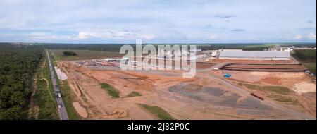 Vista panoramica aerea drone della BR-163 strada e zona deforestata con stabilimento industriale di costruzione in Amazzonia, Brasile. Ecologia, urbanizzazione. Foto Stock