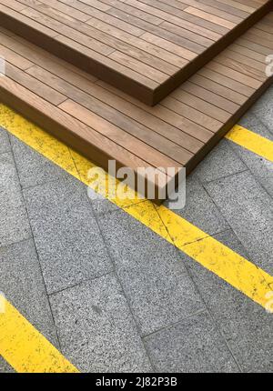 Sfondo moderno e geometrico urbano con linee gialle su piastrelle di cemento e costruzioni in legno. Foto Stock