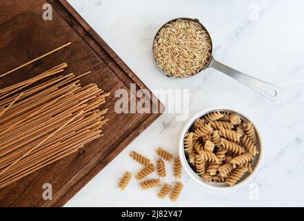 Grani sani di riso bruno, e pasta di grano intero Foto Stock