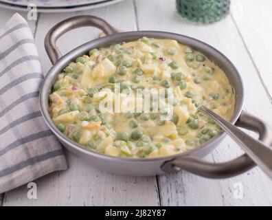 Insalata di uova con piselli verdi, cipolle rosse e maionese in un recipiente con cucchiaio Foto Stock