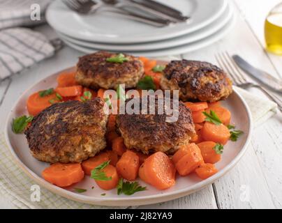 Polpette di maiale o 'frikadeller' con carote al burro su un piatto. Semplice pasto di famiglia Foto Stock