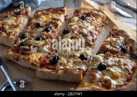 Pizza fatta in casa con tonno, cipolle, mozzarella, pomodori e olive nere Foto Stock