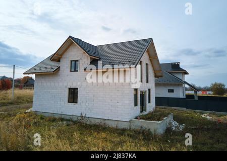 Vista aerea di casa incompiuta con pareti in calcestruzzo leggero aerato e telaio del tetto in legno rivestito con piastrelle metalliche in costruzione Foto Stock