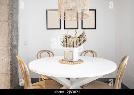 tavolo da pranzo circolare in legno bianco con sedie in legno ornamentale e pilastro in cemento Foto Stock