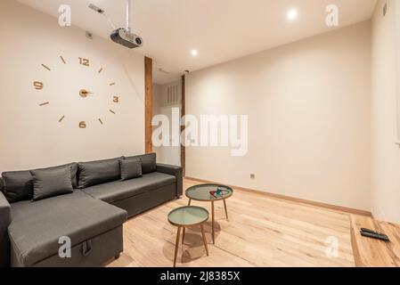 Sala cinema con proiettore, divano rivestito in tessuto scuro, 3D bicchieri su tavoli circolari e pavimento in parquet marrone chiaro in legno di castagno Foto Stock