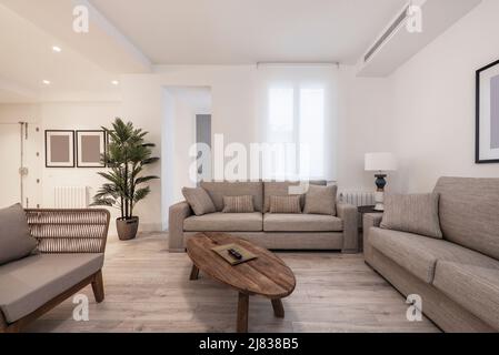 soggiorno con mobili antichi in legno, poltrone di rattan scuro e un paio di tessuto imbottito tre posti con cuscini coordinati e aria intubata Foto Stock