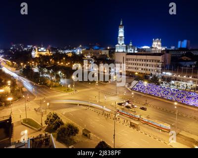 Strade notturne del centro città con tram e auto che guidano a lunga esposizione. Vista aerea sulla Cattedrale Dormition con illuminazione. Strade del centro di Khark Foto Stock