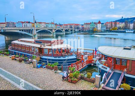 The vintage boat hotels and restaurants at the bank of Vltava River with a view of Jirasek Bridge and Smichov district on the oposite bank, Prague, Cz Stock Photo