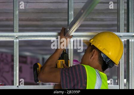 un tecnico del settore edile, che lavora come un cornamero, sta fissando un montante di supporto per soffitto alla struttura di incorniciatura interna Foto Stock