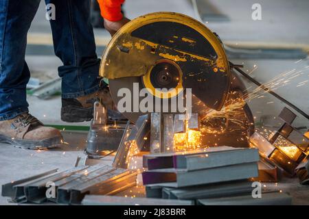 Lavoratori edili che tagliano i prigionieri per profilati in acciaio zincato per l'installazione con scintille volanti Foto Stock