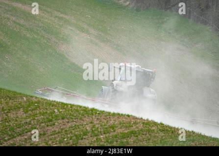 19 aprile 2022, Brandeburgo, Schwedt/OT Alt-Galow: Un agricoltore sta lavorando un campo montagnoso con il suo trattore, trascinando dietro di sé un pennacchio di polvere a causa della siccità. Foto: Soeren Stache/dpa Foto Stock