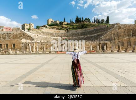 Amman, giordania - giovane ragazza con cappello in piedi a braccia aperte guardando Teatro Romano una delle attrazioni turistiche più importanti in Amman, Giordania. Foto Stock