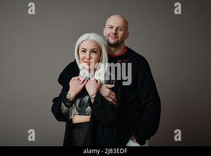 Primo piano orizzontale medio di bell'uomo caucasico maturo e donna attraente in amore indossando abiti alla moda guardando la macchina fotografica Foto Stock