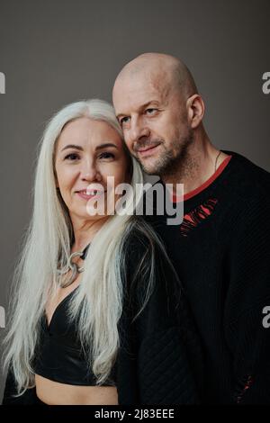 Verticale vita su studio ritratto di uomo caucasico maturo e donna indossando abiti alla moda in posa sulla fotocamera, sfondo grigio Foto Stock