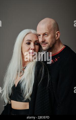 Ritratto verticale medio di bell'uomo caucasico maturo e donna attraente con lunghi capelli grigi, sfondo grigio Foto Stock