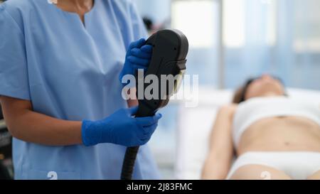 Beautician tenendo macchina ibrida di rimozione dei capelli del laser in primo piano del salone di bellezza Foto Stock