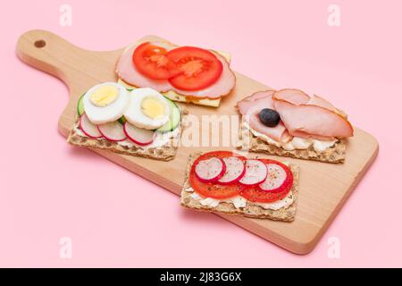 Diversi tipi di pane integrale con Prato, pomodoro, Rasth, cetriolo e formaggio. Colazione facile. Dieta alimentare. Panini veloci e sani. Croccante con gustoso ripieno. Snack dietetico sano Foto Stock