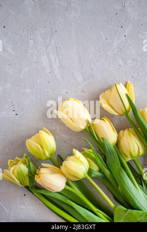 Disporre un bouquet di tulipani gialli con spago su un tavolo grigio. Foto Stock