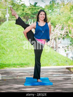 Ragazza che fa l'uccello di yoga del paradiso, una ragazza che fa lo yoga all'aperto, Una donna che fa l'equilibrio yoga, persona che fa lo yoga Svarga Dvijasana Foto Stock